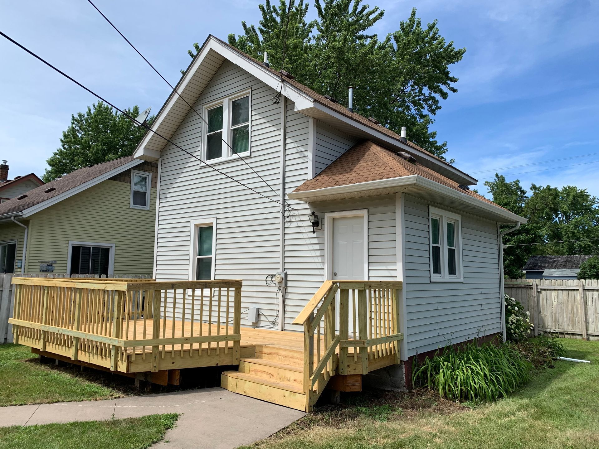 A white house with a wooden deck and stairs