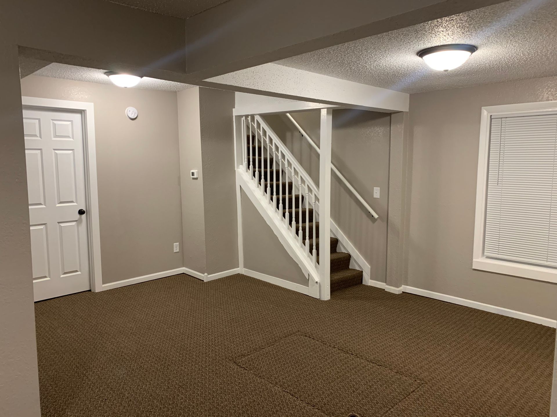 An empty basement with stairs leading up to the second floor.