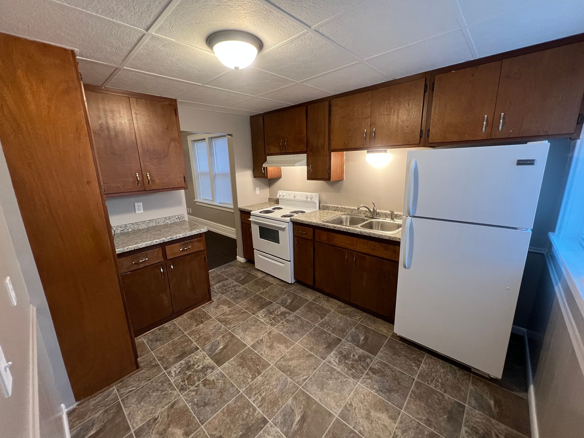 A kitchen with a refrigerator , stove , sink and cabinets.