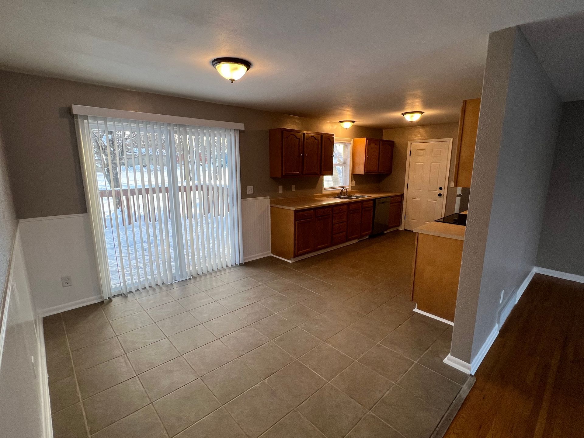 An empty kitchen with sliding glass doors and wooden cabinets.