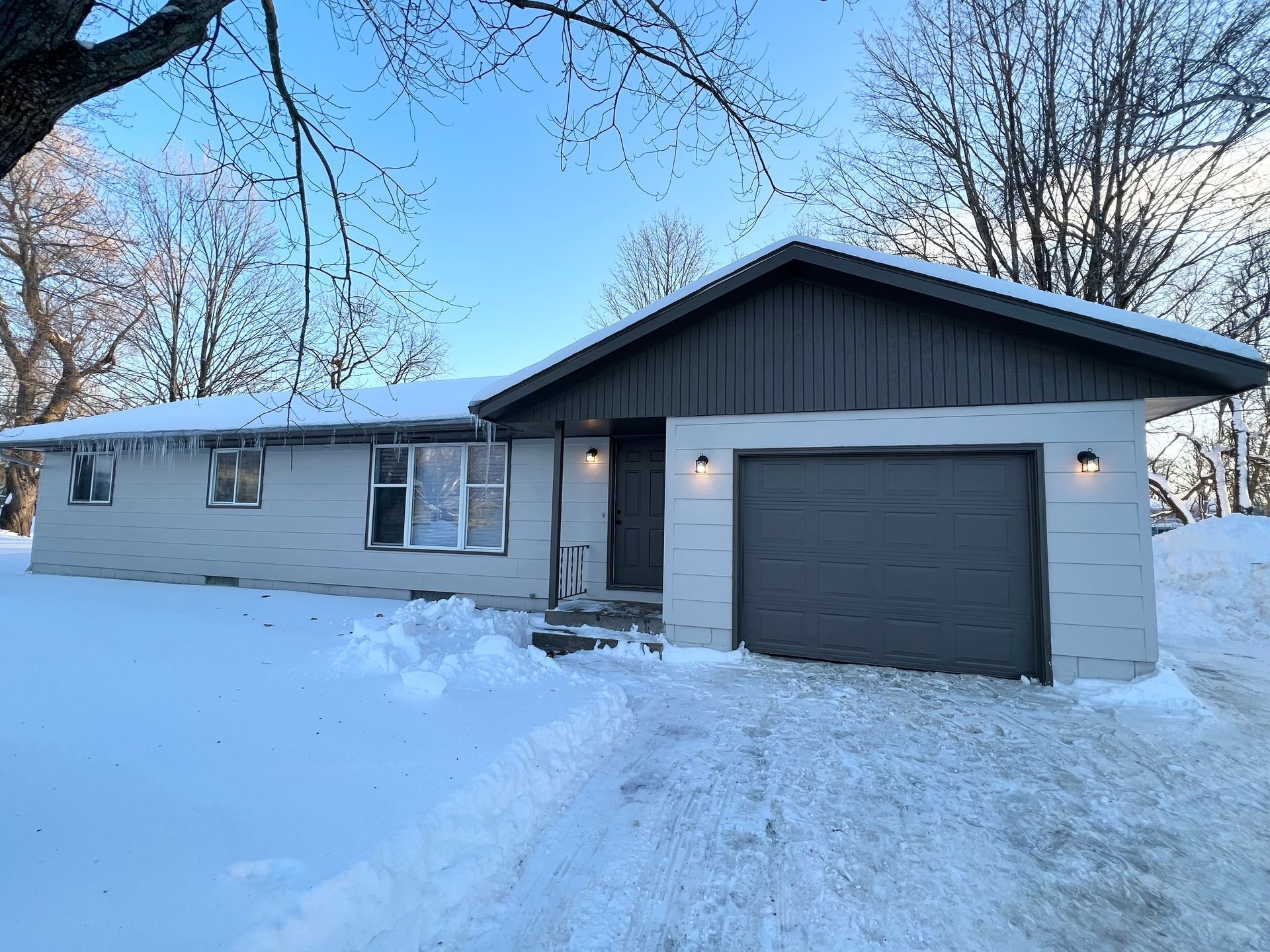 A house with a garage is covered in snow.