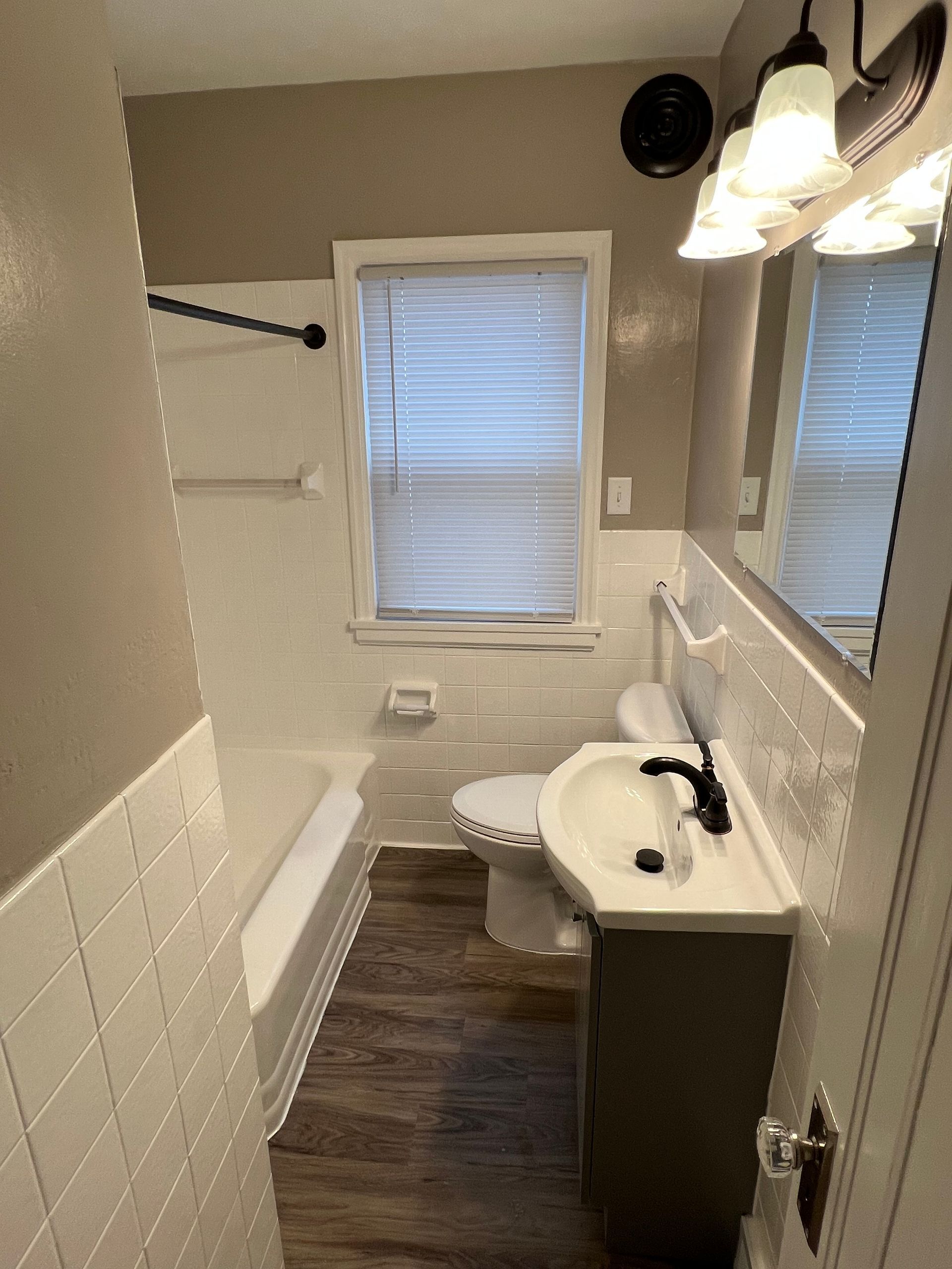 A bathroom with a sink , toilet , bathtub and mirror.