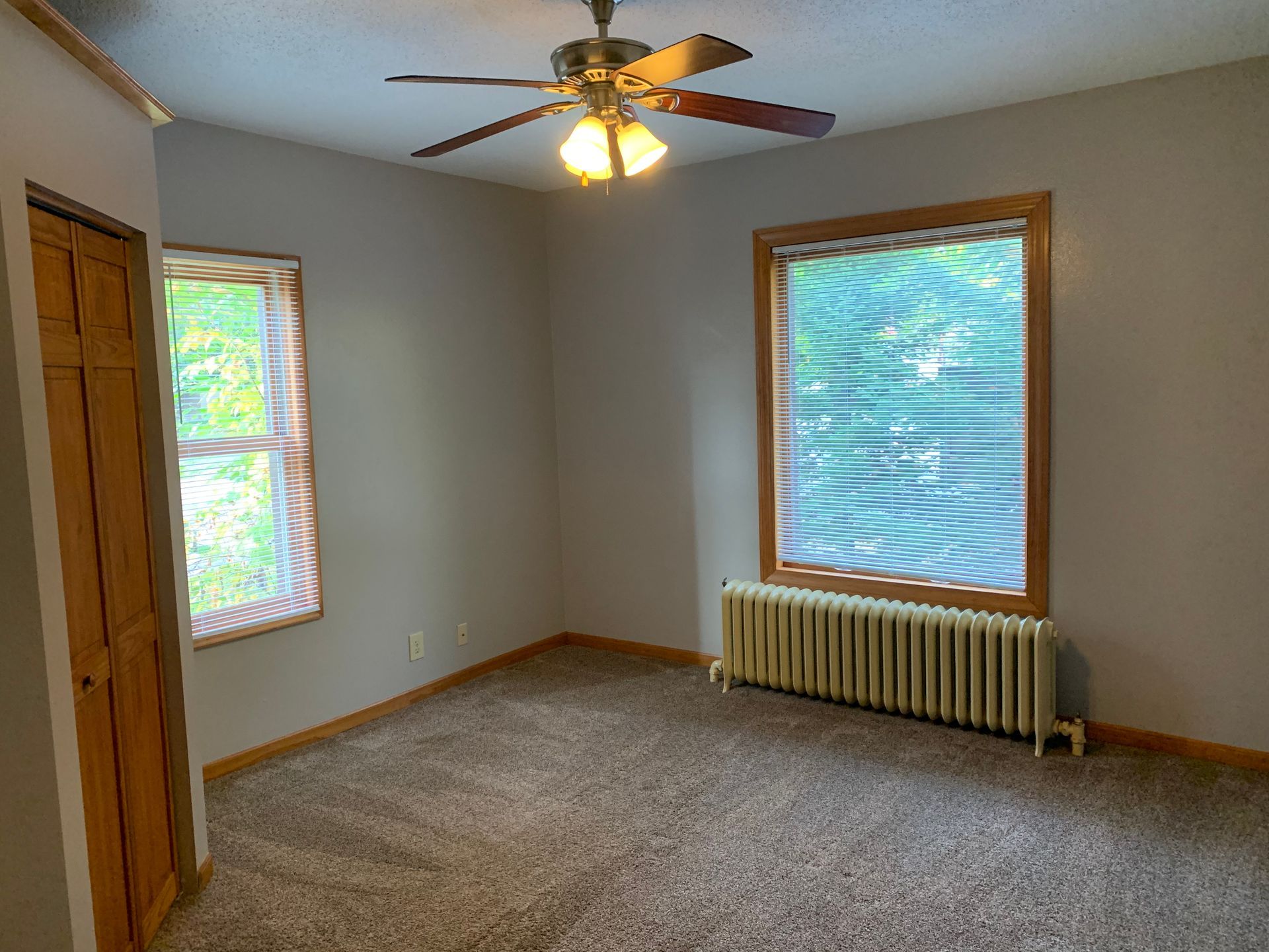 An empty room with a ceiling fan and a window.