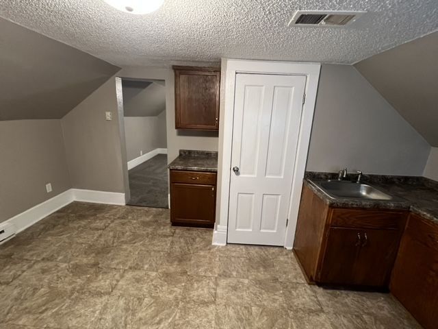 An empty room with a sink , cabinets , and a door.