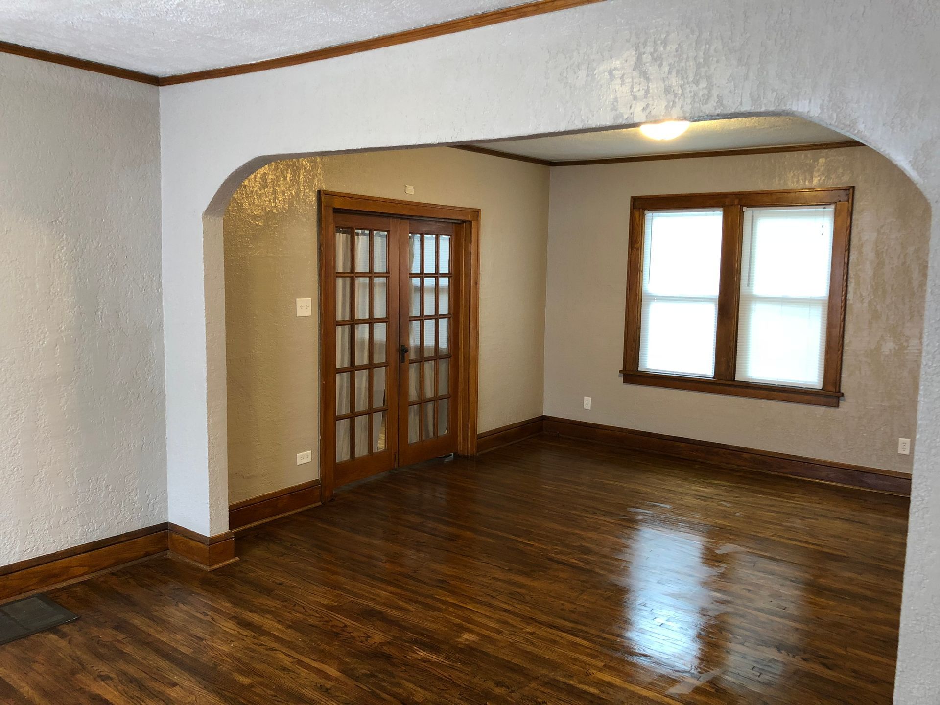 An empty living room with hardwood floors and french doors.