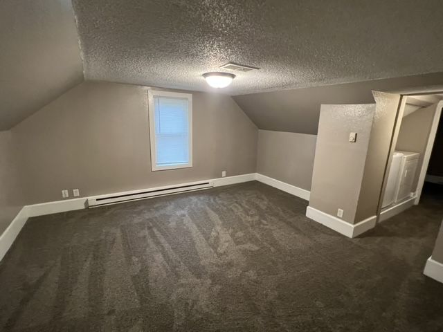 An empty room with a carpeted floor and a window.