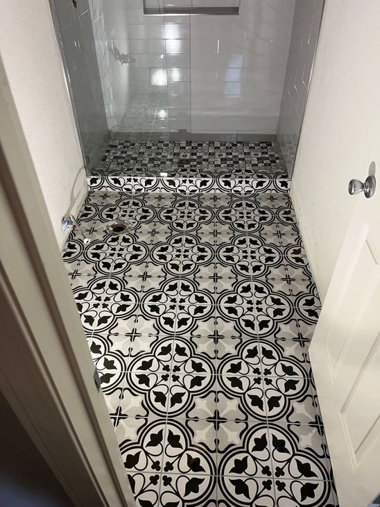 A bathroom with a black and white tile floor and a shower.