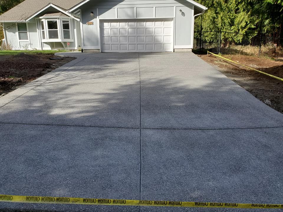 Newly installed exposed aggregate concrete driveway in front of suburban garage with clean expansion joints