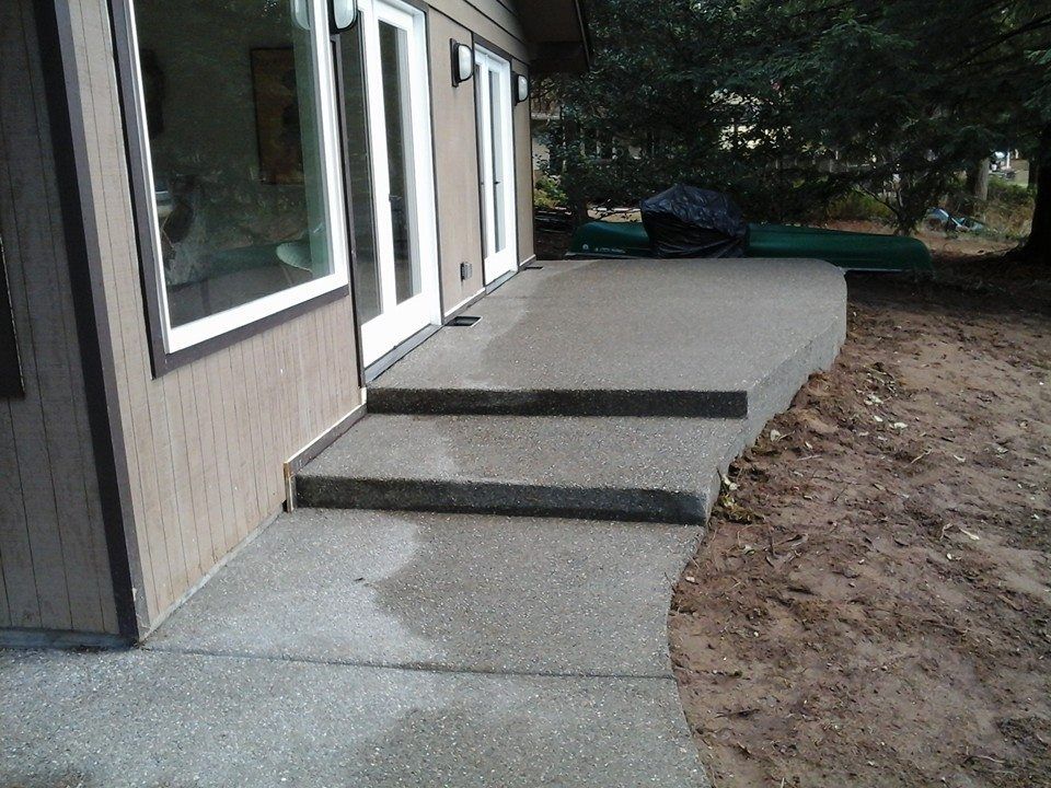Curved aggregate concrete walkway connected to backyard patio