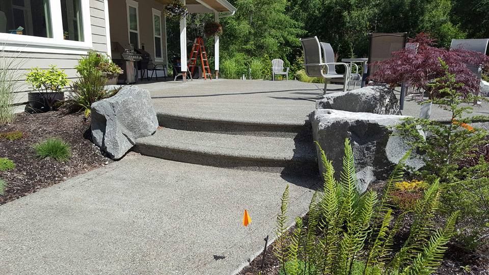 Custom aggregate concrete patio with rounded edge detailing and boulder edging