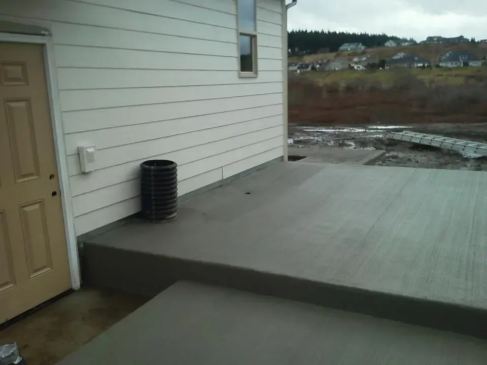Raised concrete patio slab with step-down transition and broom finish