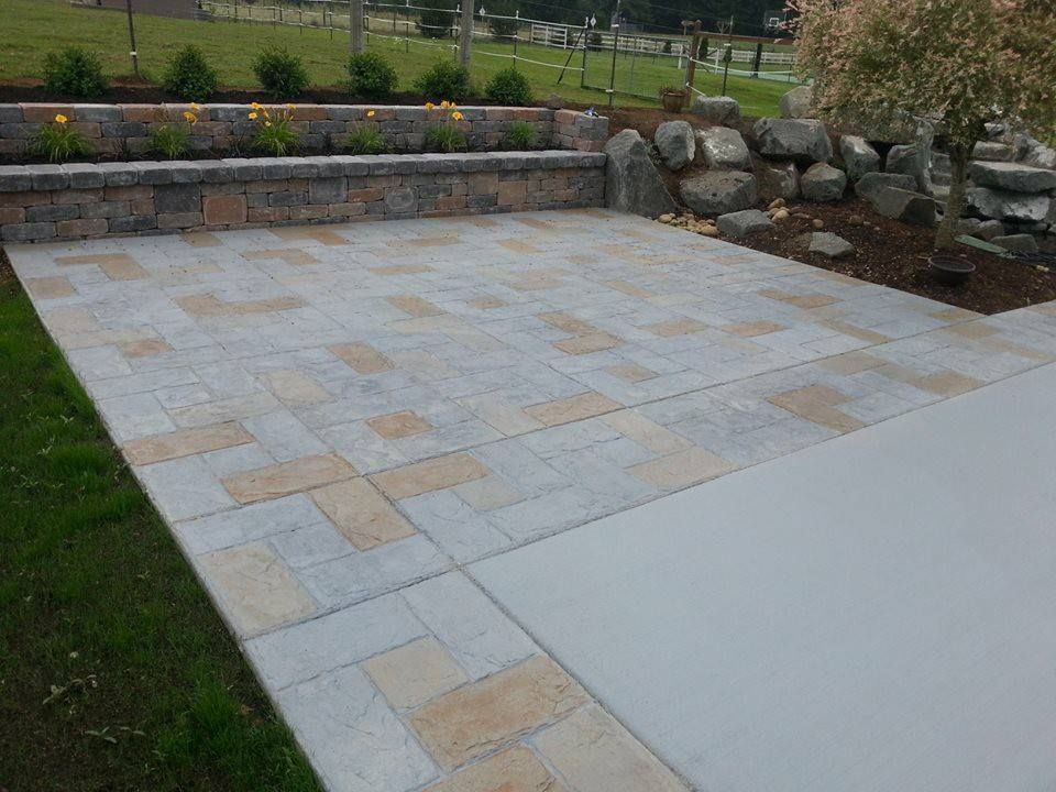 Backyard custom stained patio area set against stacked block retaining wall
