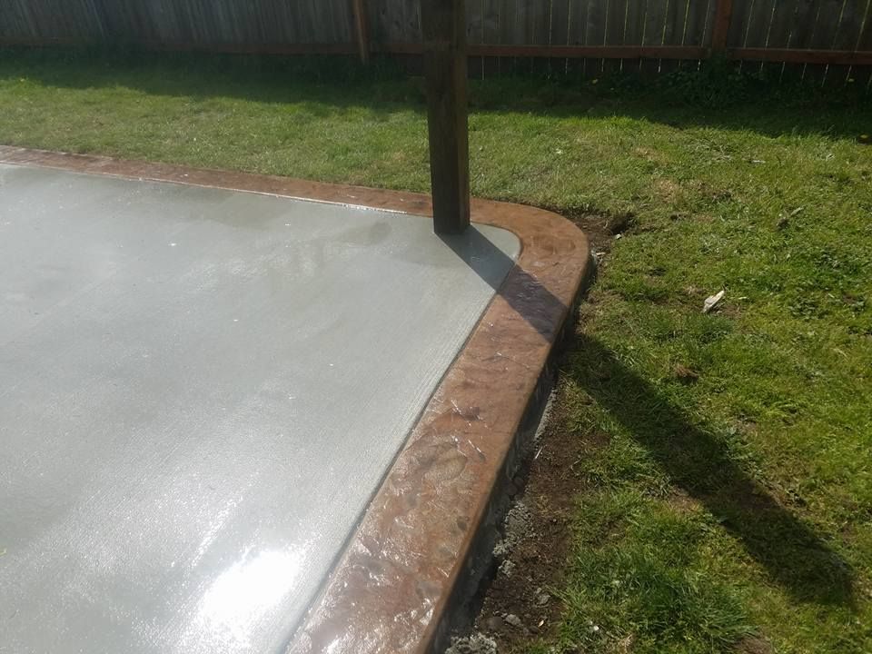 Backyard concrete installation featuring curved stamped border detail