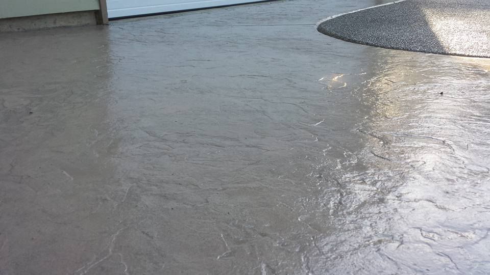 Decorative stamped driveway close up with aggregate and stained concrete
