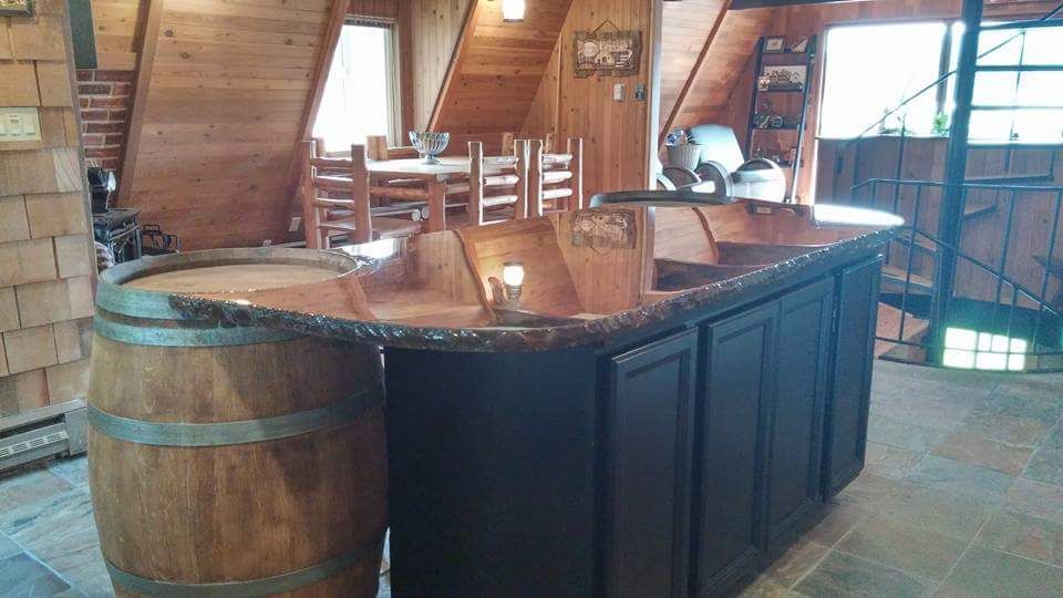 Custom concrete bar top with rustic wood barrel base in cabin style setting