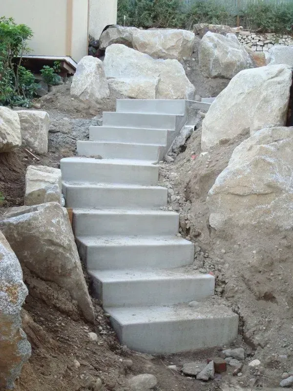 Outdoor concrete steps built into hillside with natural boulder retaining walls