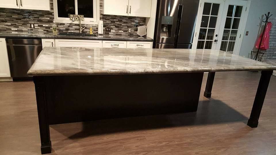 Large custom metallic epoxy concrete kitchen island with polished finish and dark wood base