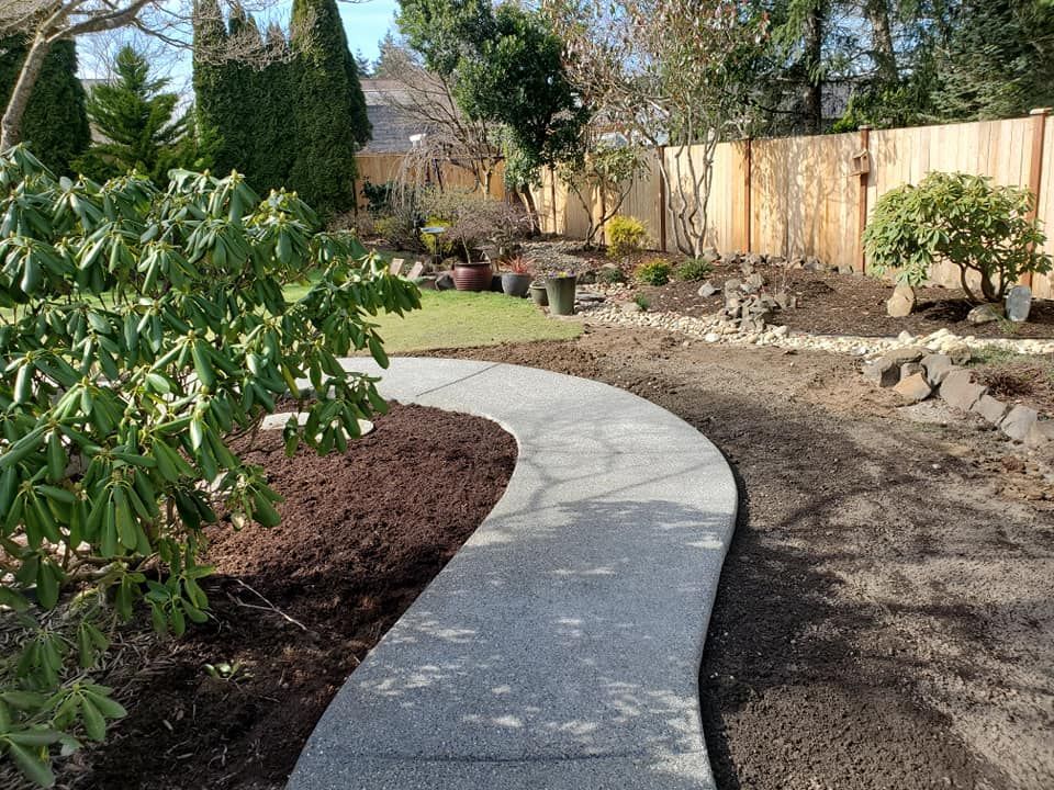 Curved exposed aggregate concrete walkway through landscaped yard