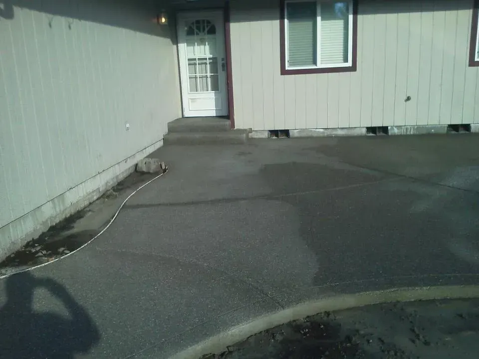 Exposed aggregate concrete patio with curved edge and sealed finish