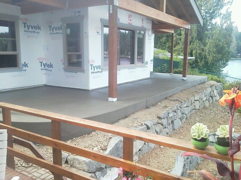 Elevated concrete patio slab supported by stone retaining wall