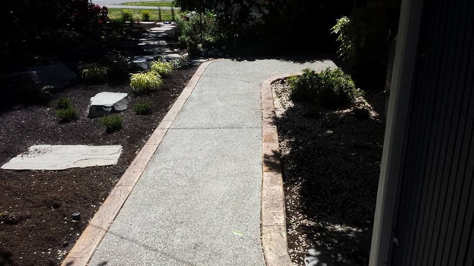 Curved exposed aggregate walkway with contrasting stamped concrete border