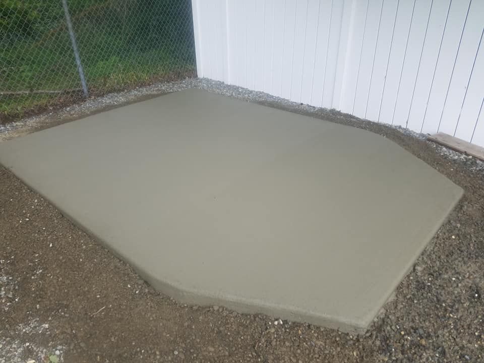 Residential concrete pad installation near fence line