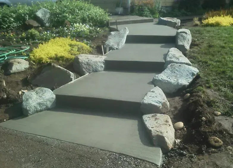 Finished concrete landscape steps with smooth broom finish and rock borders
