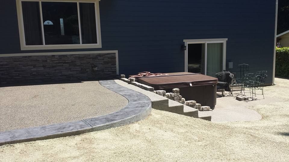 Custom aggregate concrete patio installation with curved stamped border
