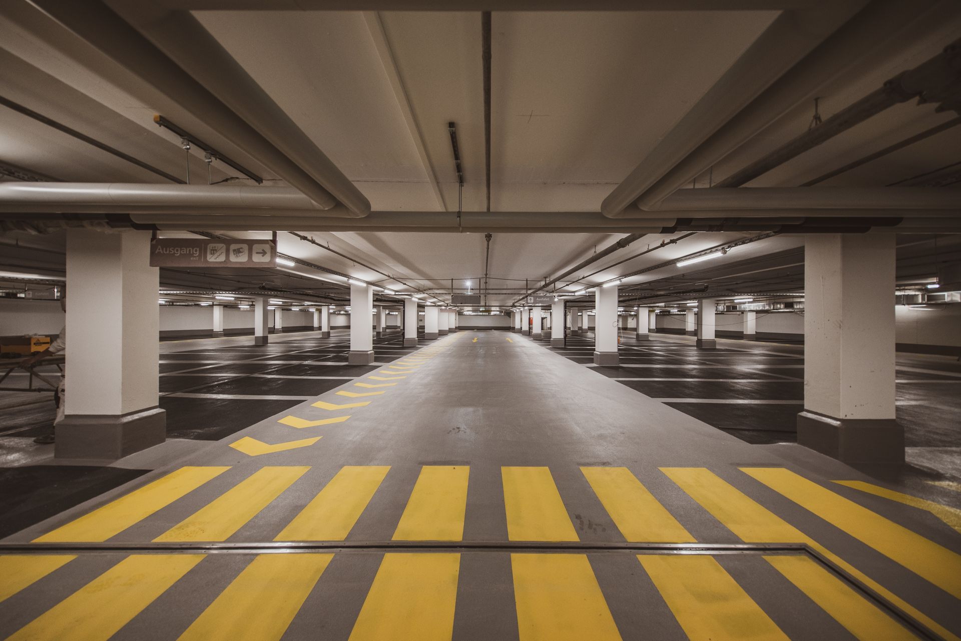 An empty underground parking lot in a shopping mall, with rows of vacant parking spaces and dimly lit surroundings.
