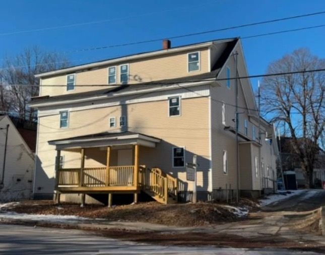 A row of houses with snow on the ground in front of them.