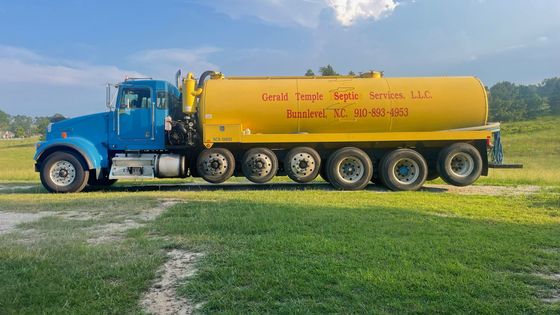 A blue and yellow tanker truck is parked in a grassy field.