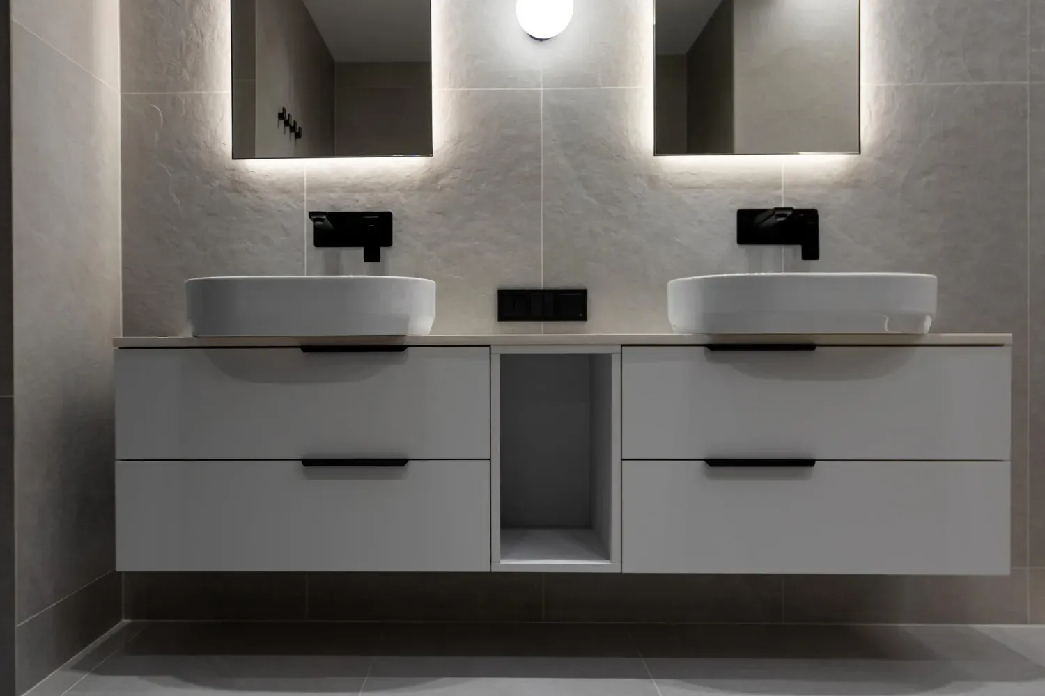 Modern bathroom vanity with double sinks, mirrors, and wall-mounted faucets in a gray minimalist interior