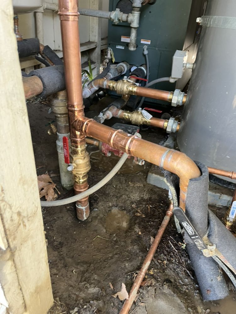 Copper pipes and fittings for plumbing in a utility area.