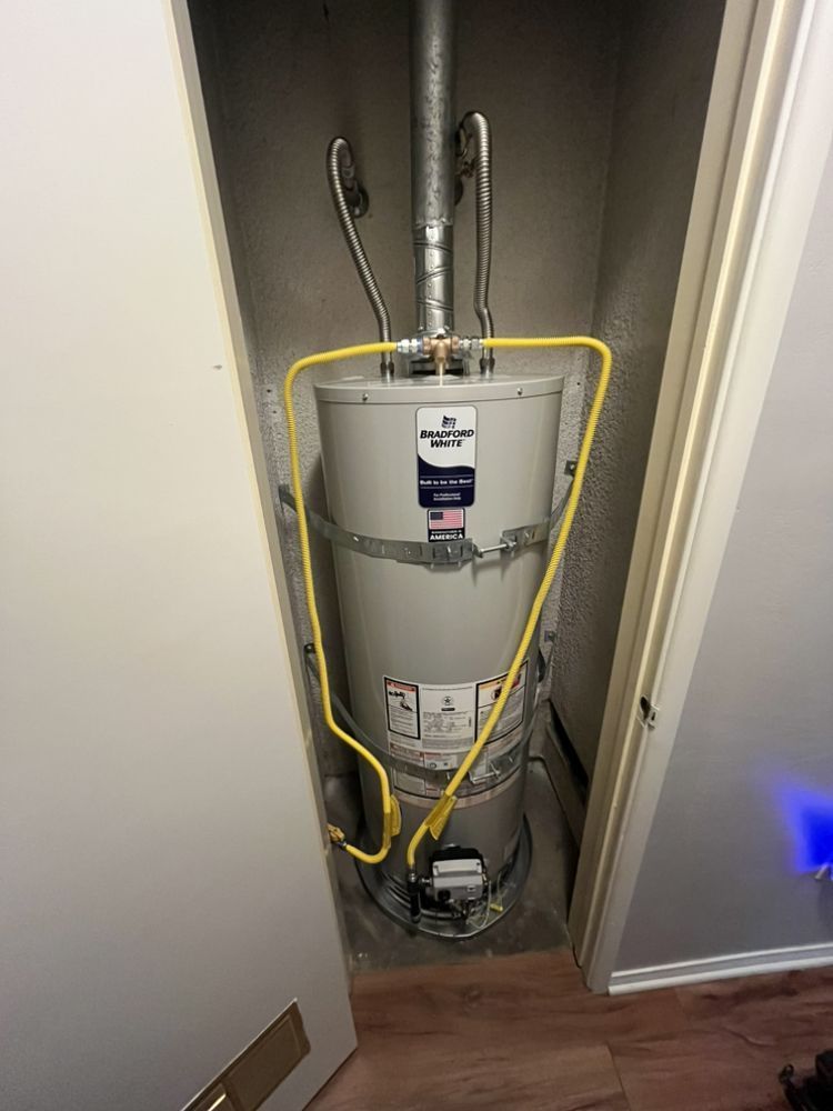 A water heater in a closet with yellow gas lines, pipes, and vents.