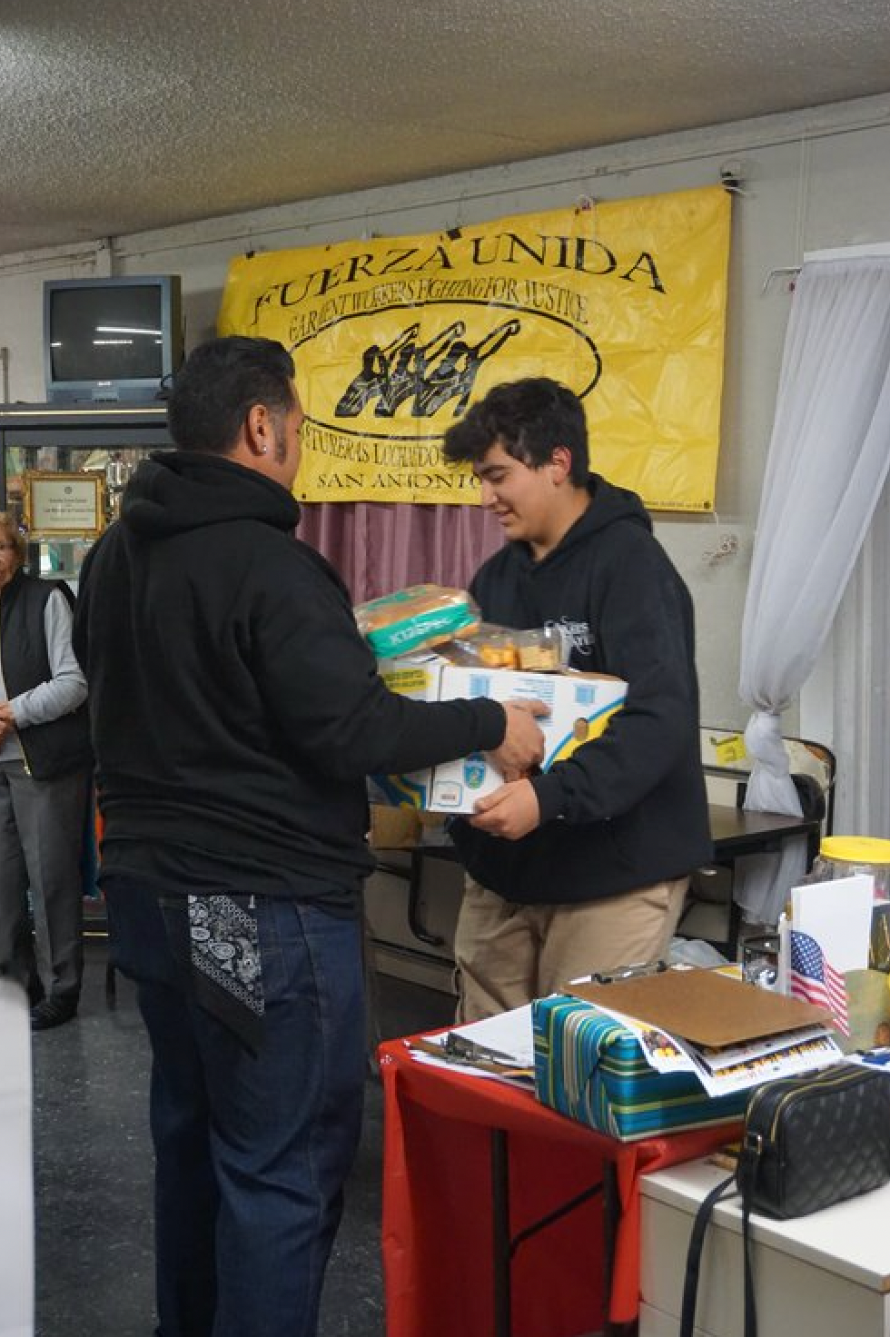 Two men are standing in front of a yellow banner that says fuerza unida