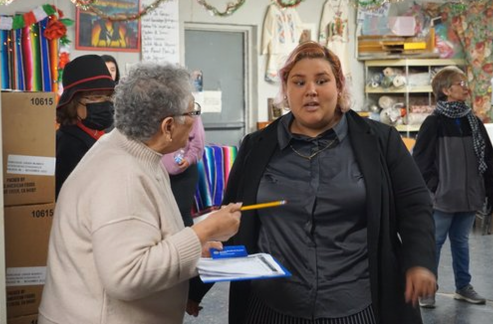 A group of people are standing in a room talking to each other.