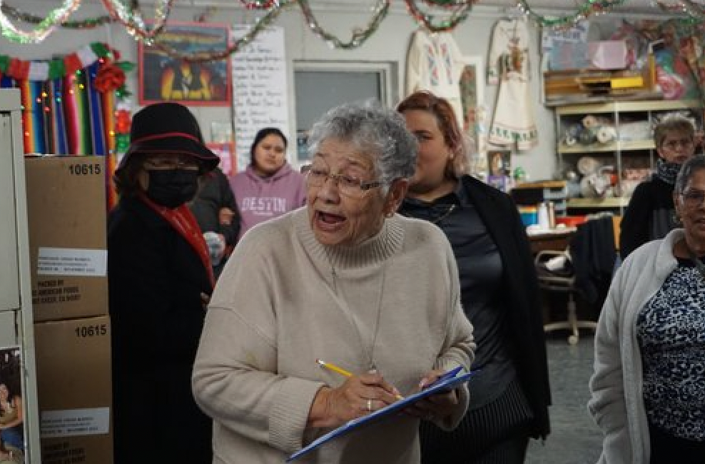 A woman is holding a clipboard and talking to a group of people.