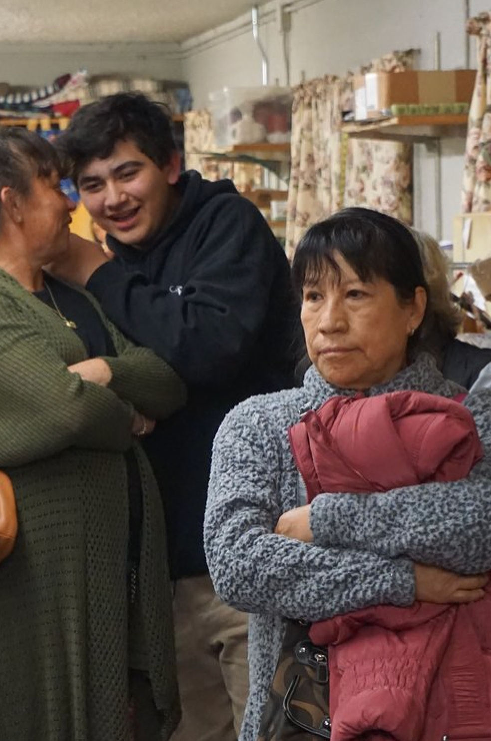 A group of people are standing in a room talking to each other.