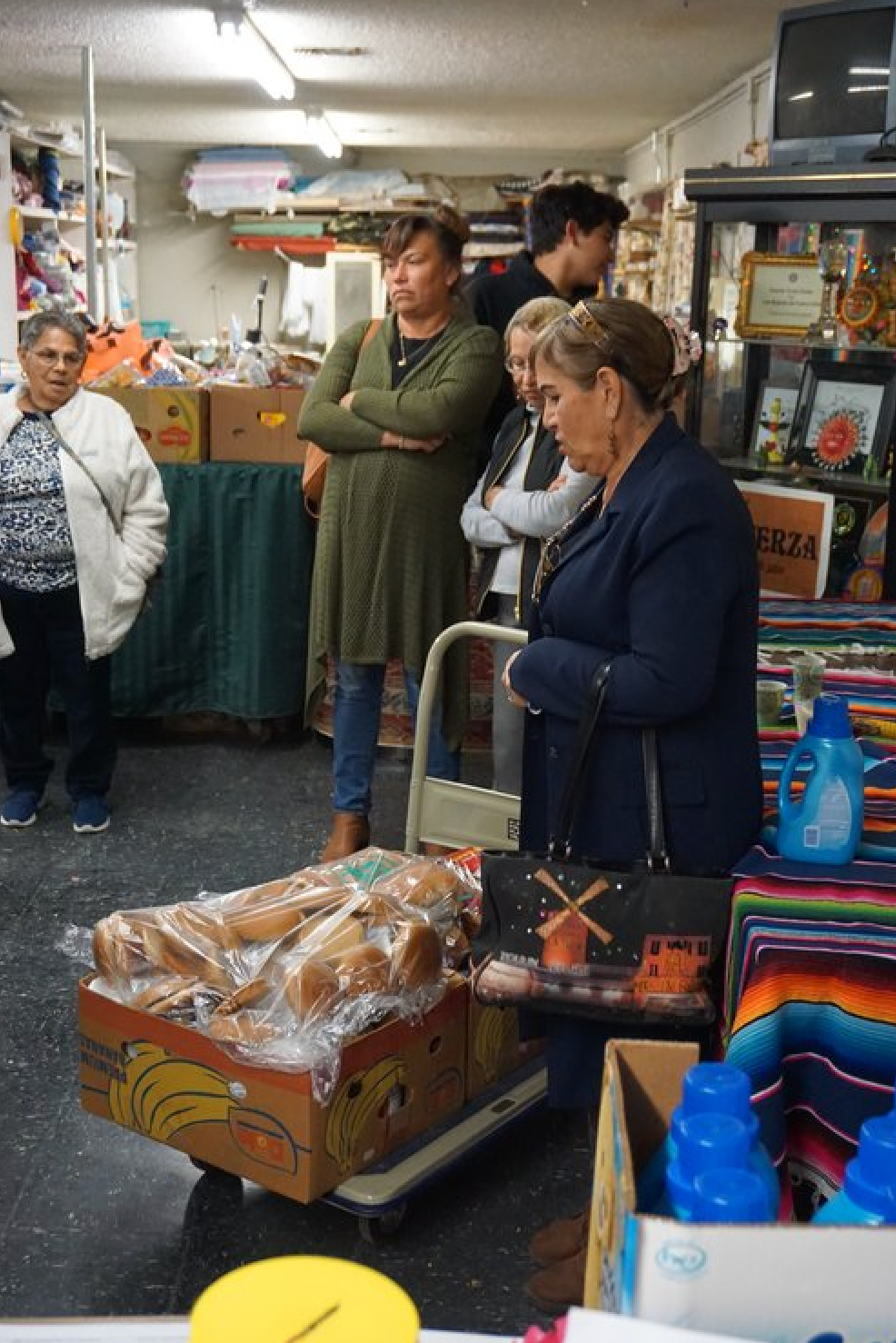A woman is standing next to a cart full of bread.