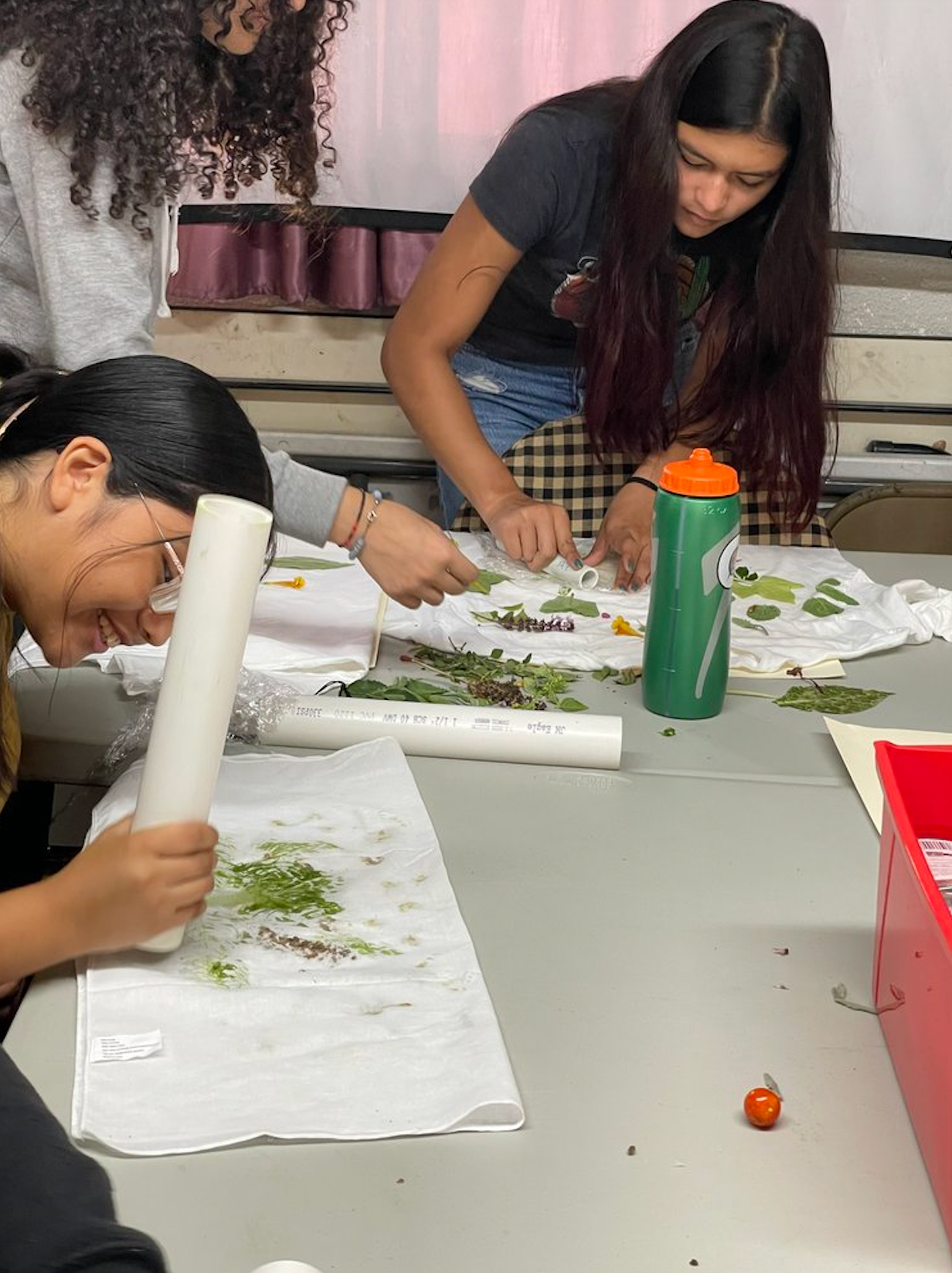 A group of girls are sitting at a table working on a project.