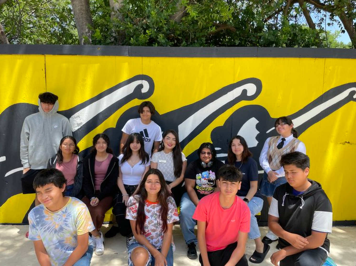 A group of young people are posing for a picture in front of a coca cola mural.