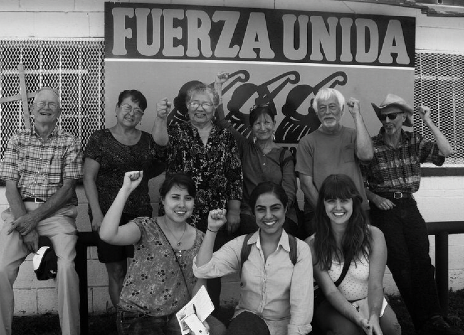 A group of people standing in front of a sign that says fuerza unida