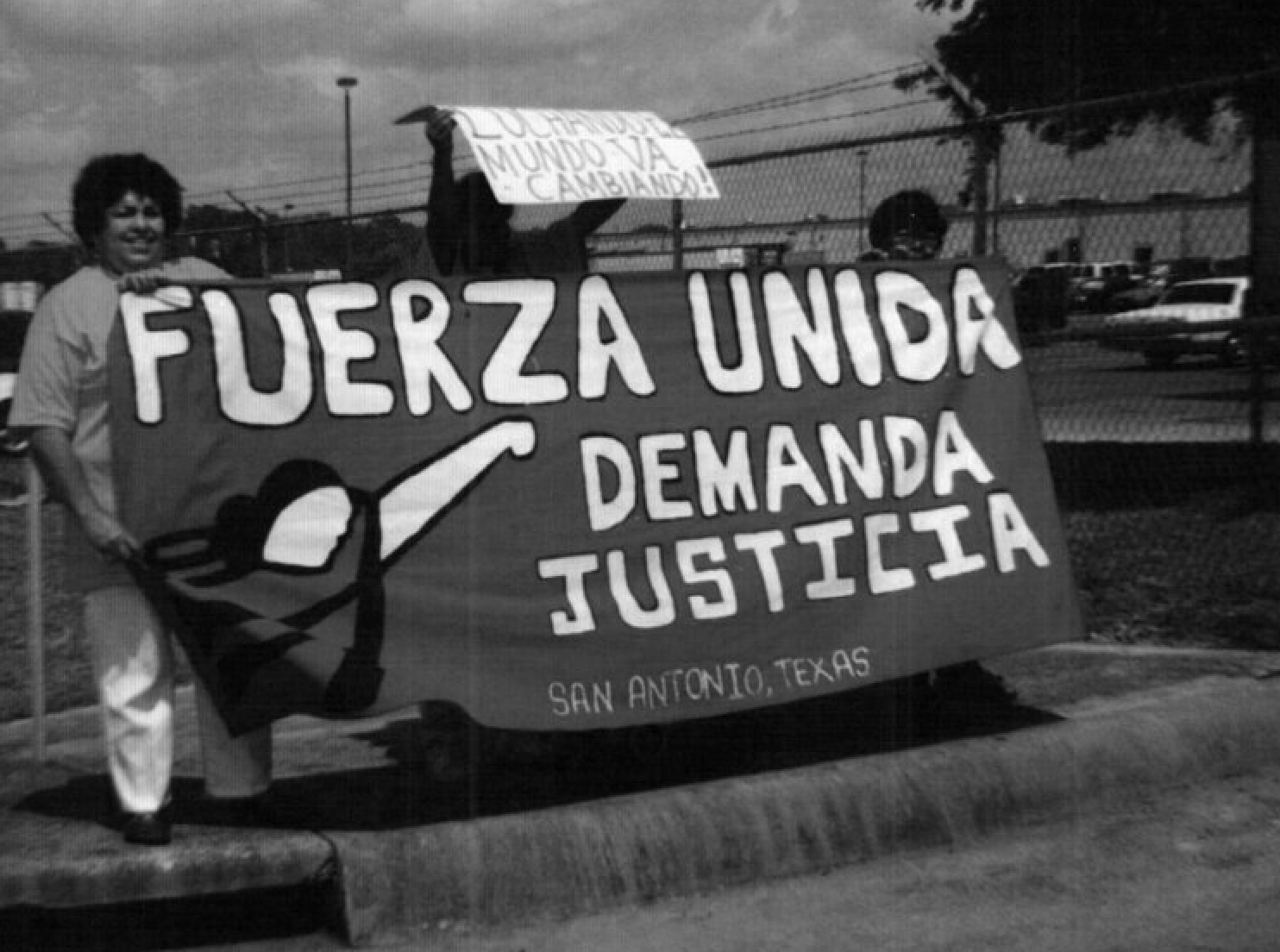 A black and white photo of people holding a sign that says fuerza unida demanda justicia