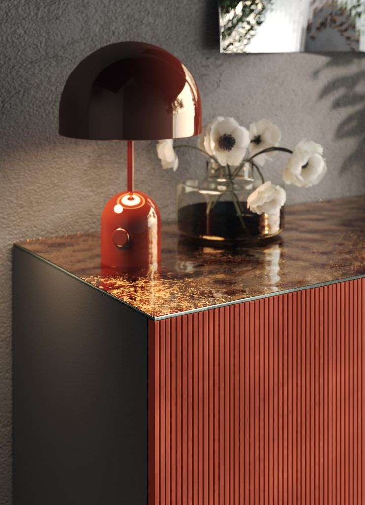 Un vaso di fiori è appoggiato su un tavolo accanto a una lampada.