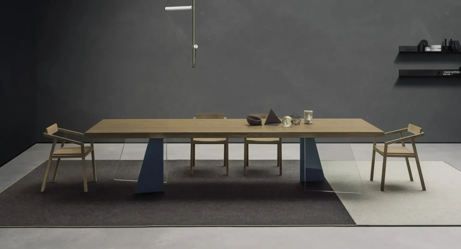 Tavolo da pranzo moderno con panche in una stanza scura e minimalista, adagiato su un tappeto grigio
