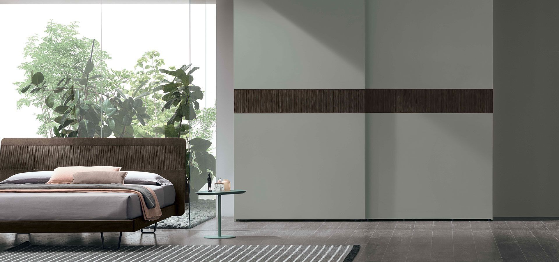 Camera da letto moderna con letto basso, ampia finestra, piante e pannelli guardaroba bianchi minimalisti.