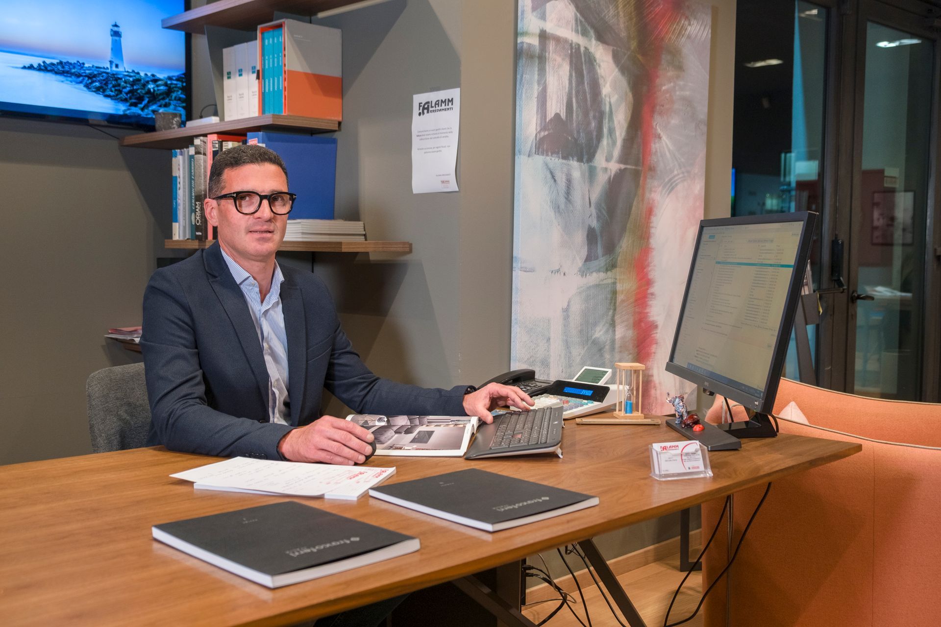 Un uomo in giacca e cravatta è seduto alla scrivania davanti a un computer.