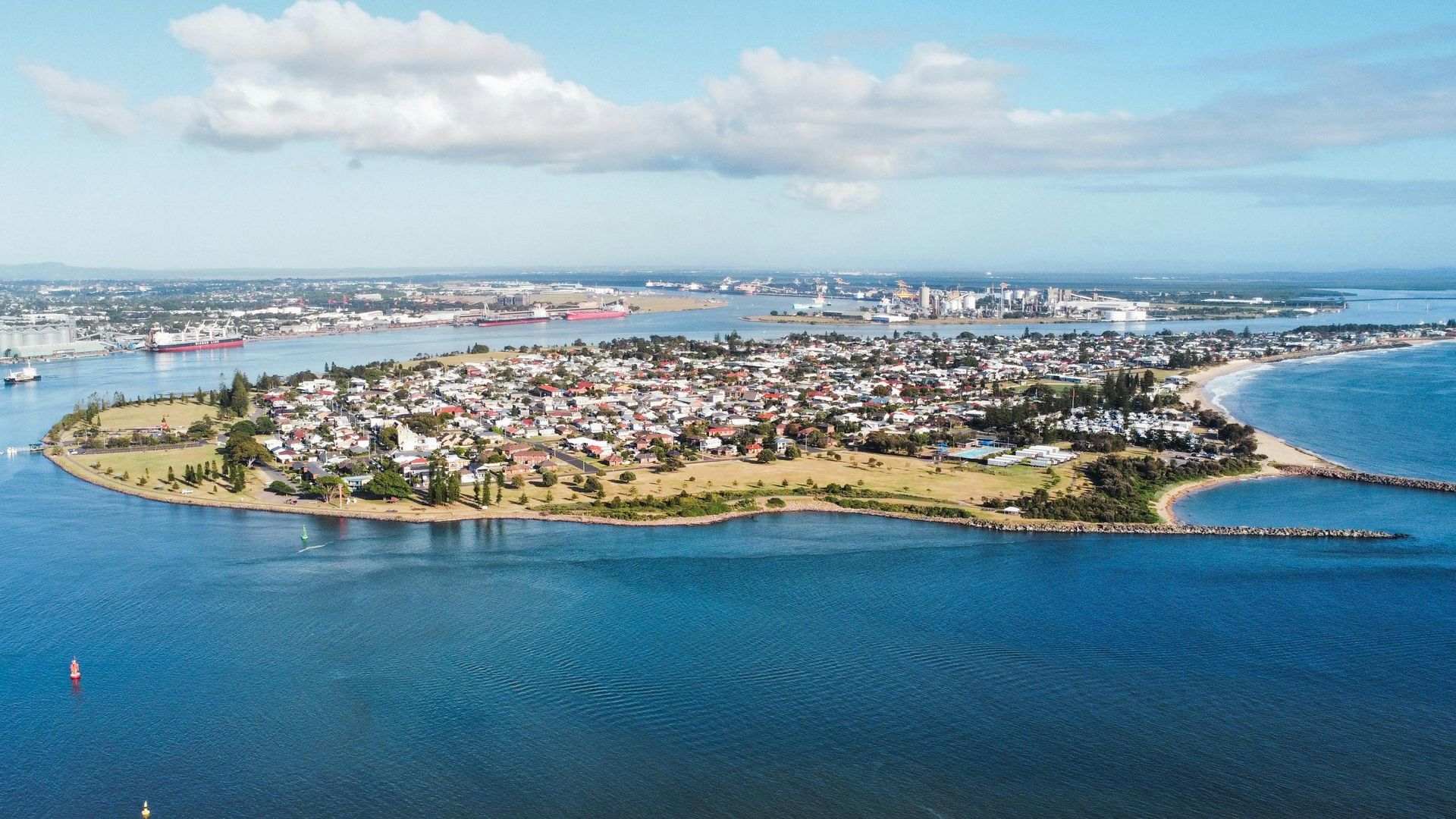 Aerial view of a small tropical island surrounded by blue water, with houses and a bridge to the mainland