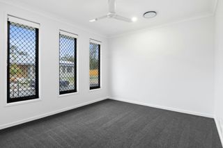 Empty room with dark carpet, three windows with black frames, and white walls.