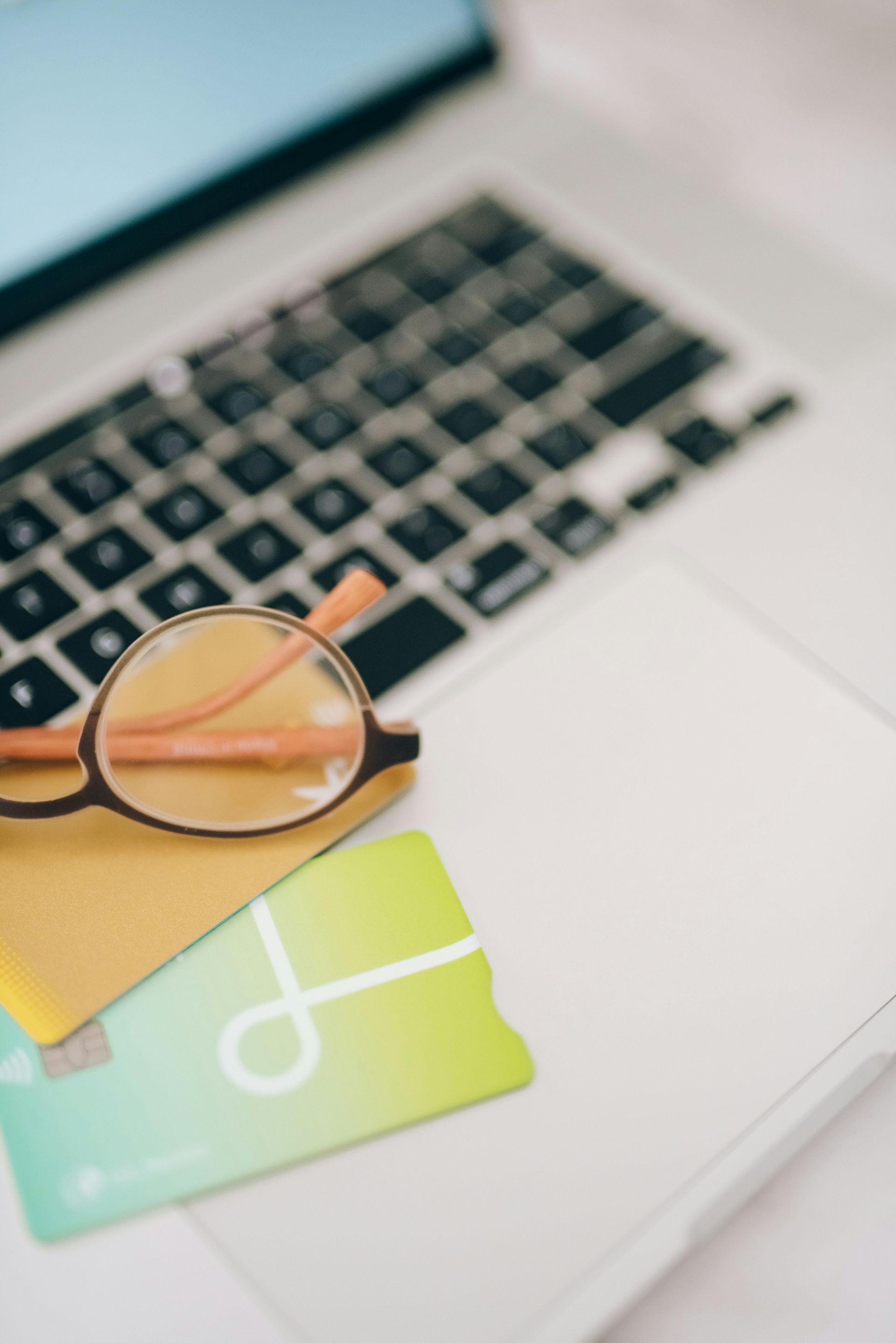Glasses on colorful cards resting on a laptop keyboard and trackpad